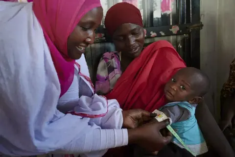 طفل سوداني يجلس أمام خيمة في أحد مخيمات النزوح بإقليم دارفور، وإلى جانبه والدته تحمل وعاءً من المياه، في مشهد يعكس معاناة الأطفال من سوء التغذية ونقص المياه الآمنة في منطقة جبل مرة.