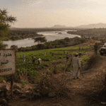 ماذا تريد إثيوبيا من السودان حدود الفشقة بين السودان وإثيوبيا، تظهر الأراضي الزراعية والمزارعين، مع خلفية لنهر النيل الأزرق، تعكس النزاع الحدودي وأهمية المياه